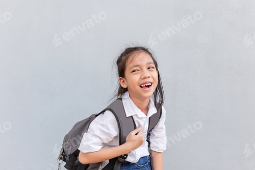Visualização: Menina feliz em uma camisa branca olhando para a câmera com fundo de parede cinza