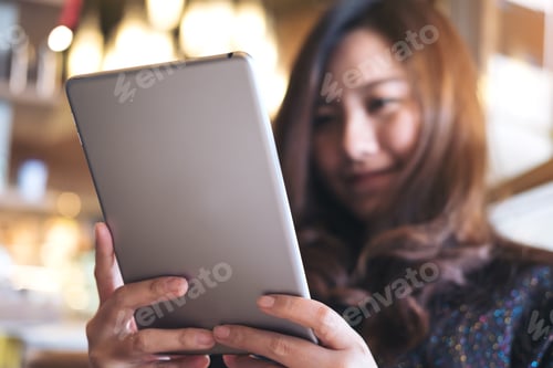 Preview: A Beautiful Asian Woman With Smiley Face Holding And Using Tablet Pc In Modern Cafe