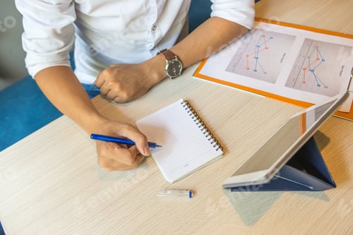 Preview: High Angle View Of Hand Writing Notebook Next To Tablet