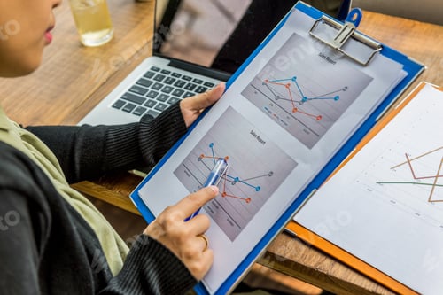 Preview: Closeup Of Female Hand Using Pen Point At Sales Report