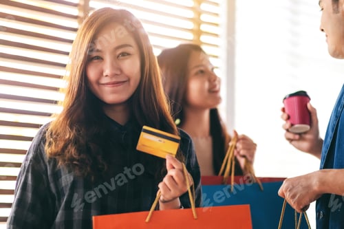 Preview: A Beautiful Asian Woman With Shopping Bags Holding And Showing A Credit Card With Friends In