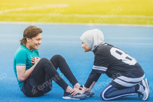 Preview: Muslim Couple Working Out Together Doing Sit Ups. Outdoor Location. Morning Sun.
