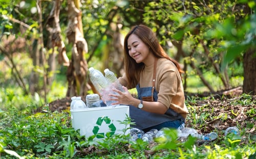 Preview: A Beautiful Young Asian Woman Collecting And Putting Plastic Bottles Into A Recycle Bin In The