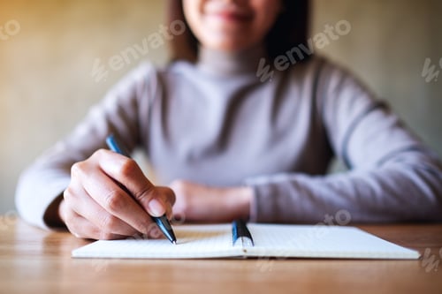Preview: Closeup Image Of A Woman Writing On A Blank Notebook On The Table