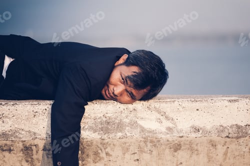 Preview: Tired Or Stressed Businessman In A Suit And Lying Down On Concrete Of Reservoir With Mountains