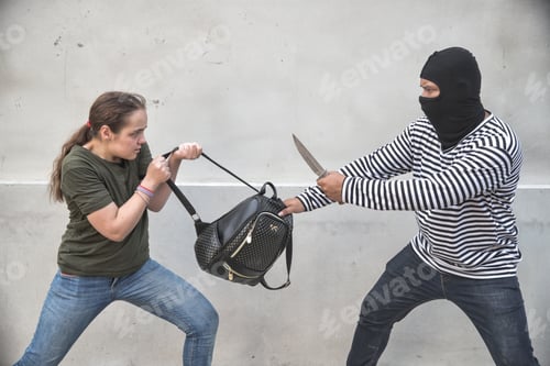 Preview: Thief Stealing Bag From Walking Woman On Street With Knife In Hand (Theft Concept)