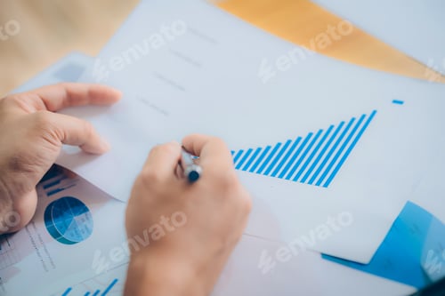 Preview: Business Man Working At Office With Laptop, Tablet And Graph Data Documents On His Desk.