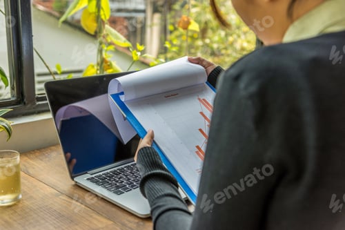 Preview: Close Up Of Woman Holding Chart Document Next To Computer
