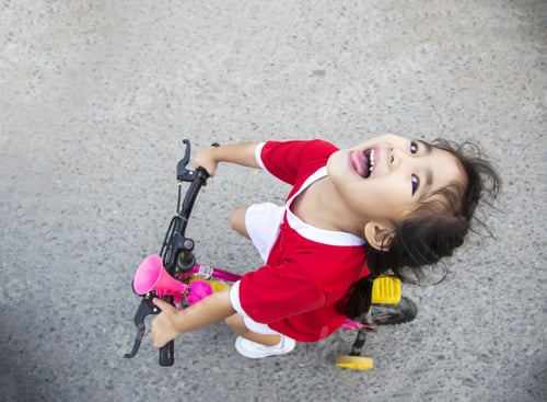 Preview: Little Girl Riding Bycicle To Adventure On The Street Background