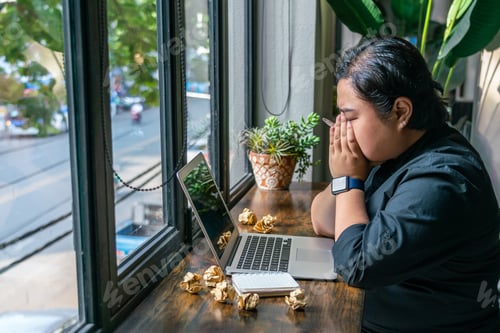 Preview: Frustrated Freelancer Sitting With Laptop, Crumpled Paper Balls On Table
