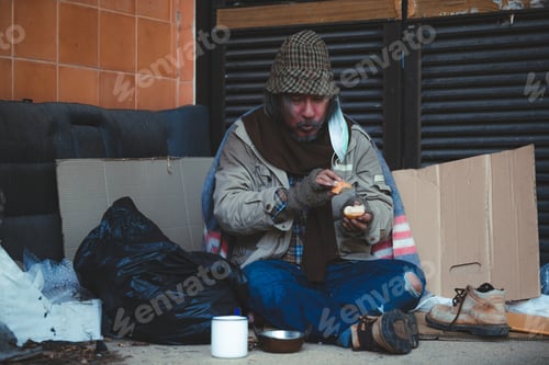 Preview: Old Homeless Man In A Green Cloak Holds Bread, Hands Where People Give Bread Or Share Food To Help