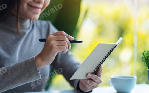 Preview: Closeup Image Of A Beautiful Young Asian Woman Holding And Writing On A Notebook