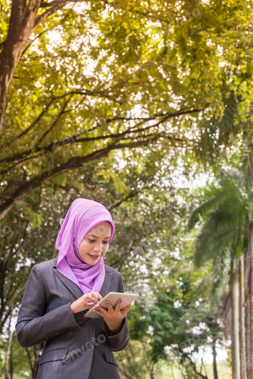 Preview: Muslim Businesswoman Looking At A Tablet At A Park.