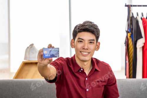 Preview: Young Asian Male Online Merchant Blogger Live Video To Sell, Holding Credit Card, Looking At