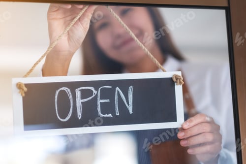 Preview: A Young Asian Entrepreneur Or A Waitress Hanging Open Sign On The Shop Front Door