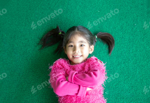 Preview: Happy Cute Asian Kid Smile On Green Grass With Pink Swetter Suite, Girl Cross Arm Action On Green