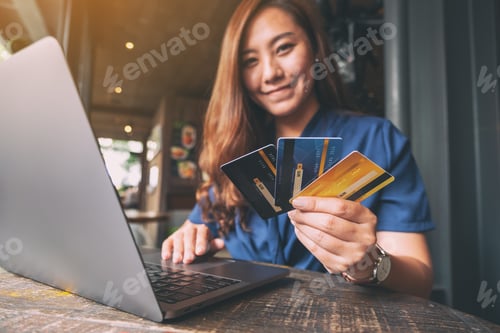 Preview: A Beautiful Asian Woman Holding Credit Cards While Using Laptop Computer