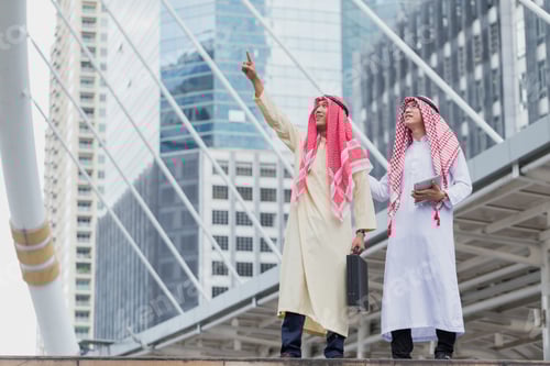Preview: Two Arab Or Muslim Business Man Standing At Front Modern Office Discussing Work With Tablet. Ethnic
