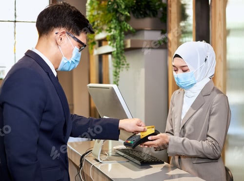 Preview: Two Persons Wearing Anti-Virus Masks Are Paying By Credit Card. Accepting Payments During The
