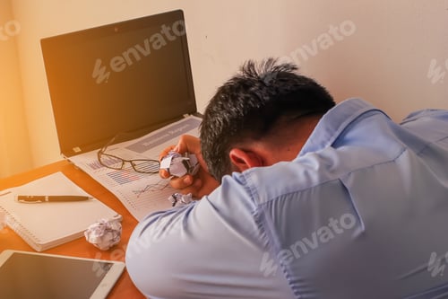 Preview: Businessman Putting His Head Down On Desk In Office