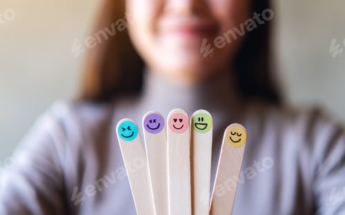 Preview: A Woman Holding Colorful Hand Draw Happy Emotion Faces On Wooden Stick