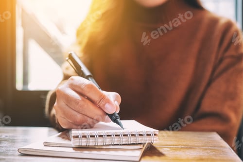 Preview: Closeup Image Of A Woman Writing On Blank Notebook With Fountain Pen On Wooden Table