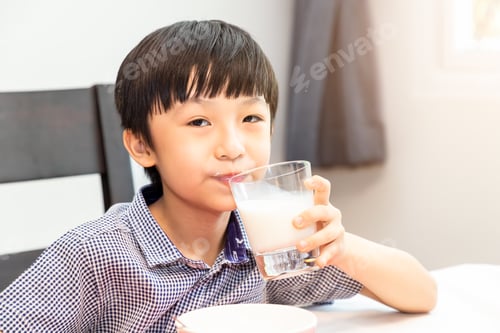 Preview: Adorable Happy Young Asian Boy Having Breakfast And Drinking Milk At Home In The Morning; Looking