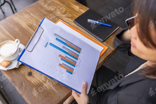 Preview: Close Up Photo Of Woman Reading Sales Chart Document