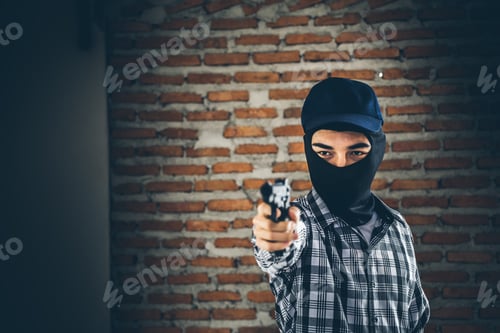 Preview: Robber Holding A Gun. Low Key Photo And Selective Focus. Criminality Concept.
