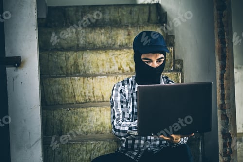 Vista previa: Computer Hacker Of Terrorist Stealing Information With Laptop In Abandoned Building. Low Key Photo.