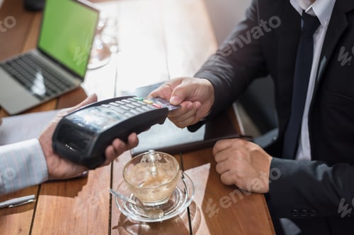 Preview: Businessman Paying By Credit Card With A Credit Card Reader Machine In A Restaurant