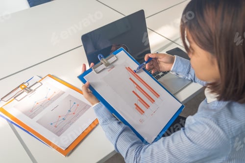 Preview: Young Businesswoman In Blue Shirt Reading Financial Reports In The Business Office