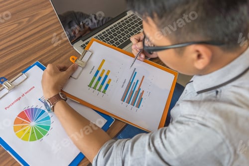 Preview: Young Man Holding Pen Pointing At The Graph In Document
