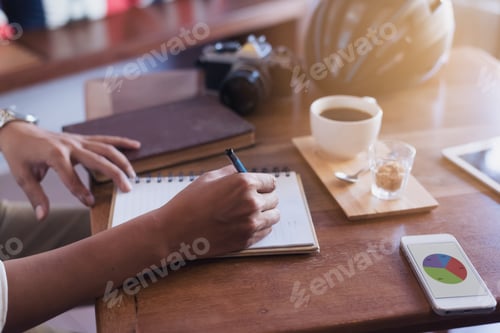 Preview: Casual Business Man Writing Book With A Phone And A Camera On The Coffee Table.