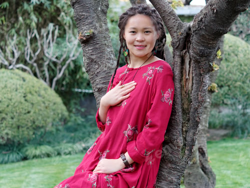 Preview: Portrait Of A Beautiful Chinese Girl In Red Robe With Cute Dreadlocks Leaning On Tree And Smiling