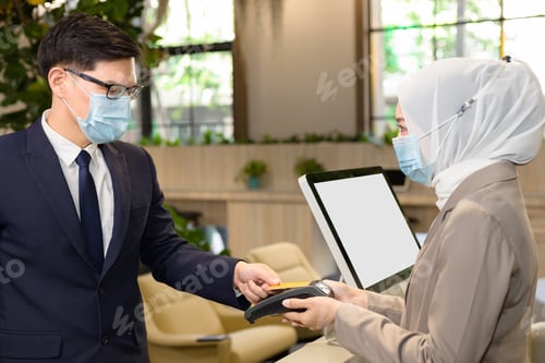 Preview: Two Persons Wearing Anti-Virus Masks Are Paying By Credit Card. Accepting Payments During The