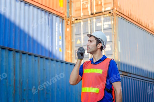 Preview: Foreman In Hardhat And Safety Vest Talks On Two-Way Radio Control Loading Containers Box From Cargo