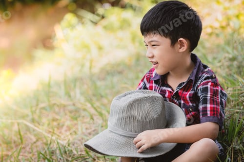 Preview: Boy Outdoors Wearing Plaid Shirt Holding Straw Hat