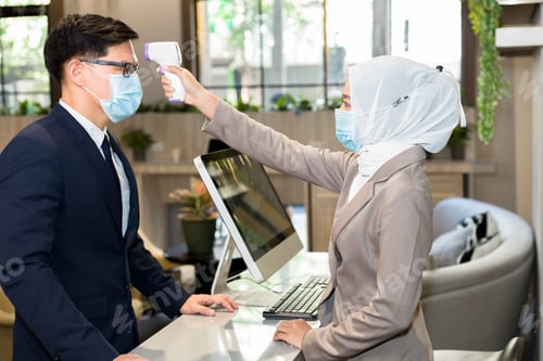Preview: Muslim Female Receptionist Measures Tourists' Temperatures Before Staying In A Hotel.