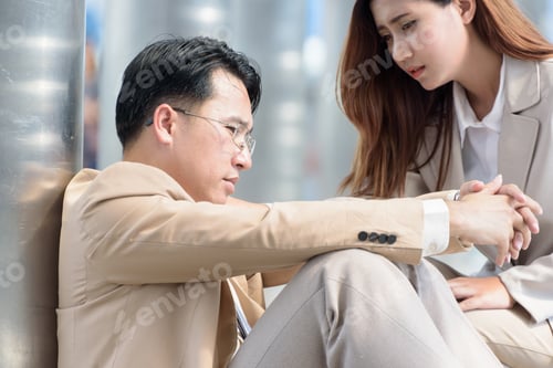 Preview: Businesswoman Comforting A Sad Businessman Sitting On The Street In The City