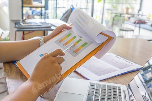 Preview: Asian Employee Checking Sales Report In Office Room