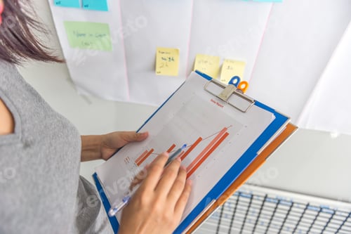 Preview: Woman Hand Holding Pen Pointing At The Sales Reports