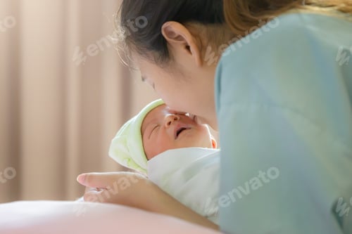 Preview: Selective Focus Of Asian Mother Kissing Newborn Baby Boy Sleeping In Hand At Hospital