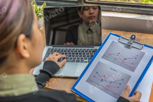 Preview: Rear View Of Woman Working With Laptop And Diagram Document