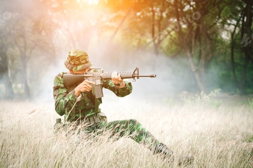 Preview: Soldier Sitting On The Ground And Camouflage In Grass. Soldier Holding Gun Weapon And Waring Armor