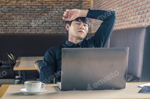 Preview: Man With His Hand Holding His Face Taking A Brake From Working With Laptop Computer And Notebook In