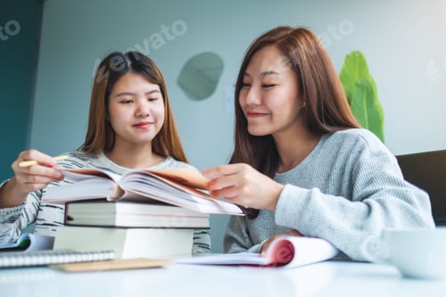 Preview: Two Young Female Students Tutoring And Catching Up Workbook Together
