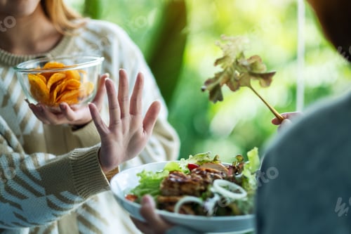 Preview: Women Choosing To Eat Potato Chips And Making Hand Sign To Refuse A Vegetables Salad