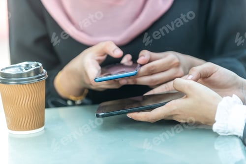 Preview: Muslim Businesswomen Playing With Their Smartphone During Their Coffee Break.