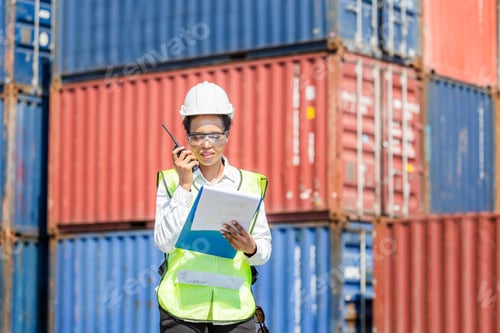 Preview: Woman Foreman In Hardhat And Safety Vest Holding Holding Clipboard Checklist And Talks On Two-Way